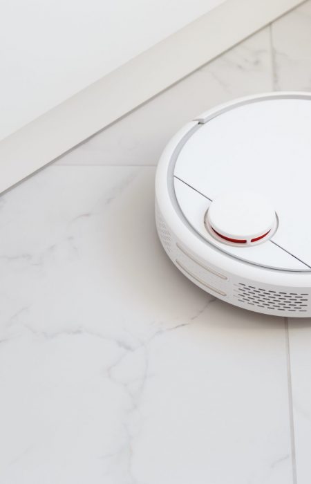 Robot vacuum cleaner vacuuming tiles in kitchen. Modern device